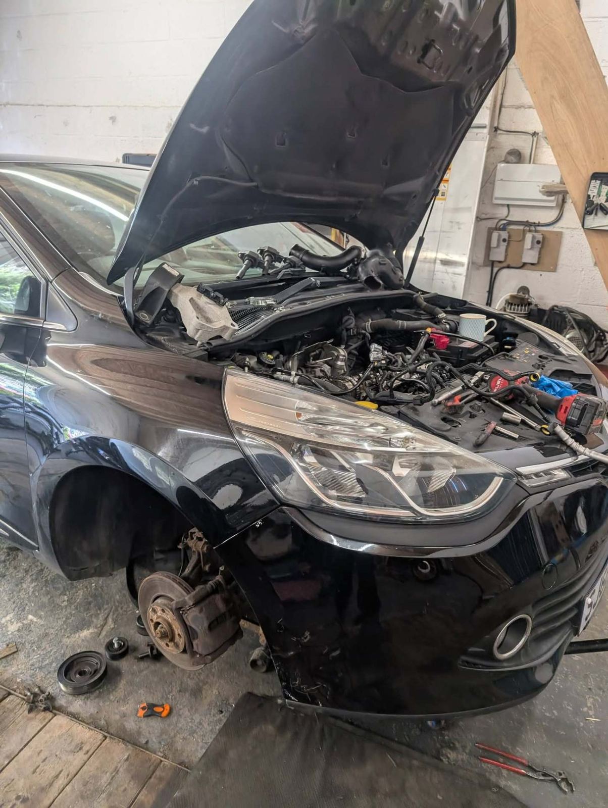 Engine work on a black hatchback in the workshop